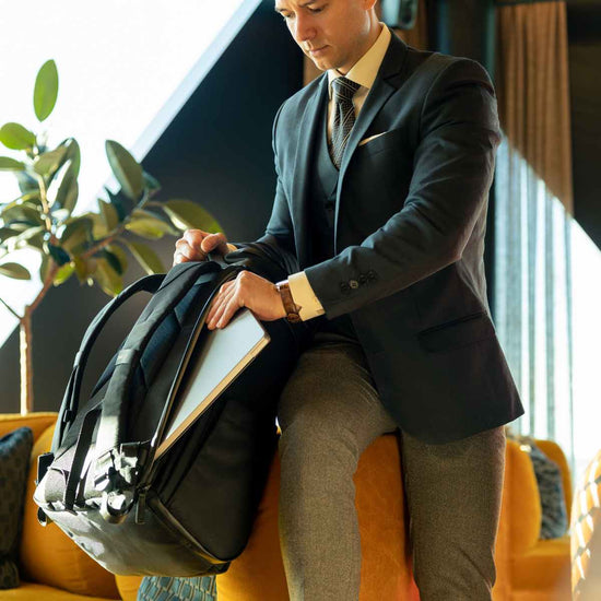 Man i kostym stoppar ner sin laptop i en ryggsäck med ett praktiskt separat laptopfack