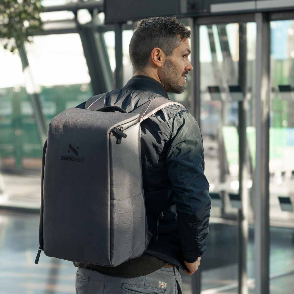 Man med en grå ryggsäck på flygplatsen som går som handbagage