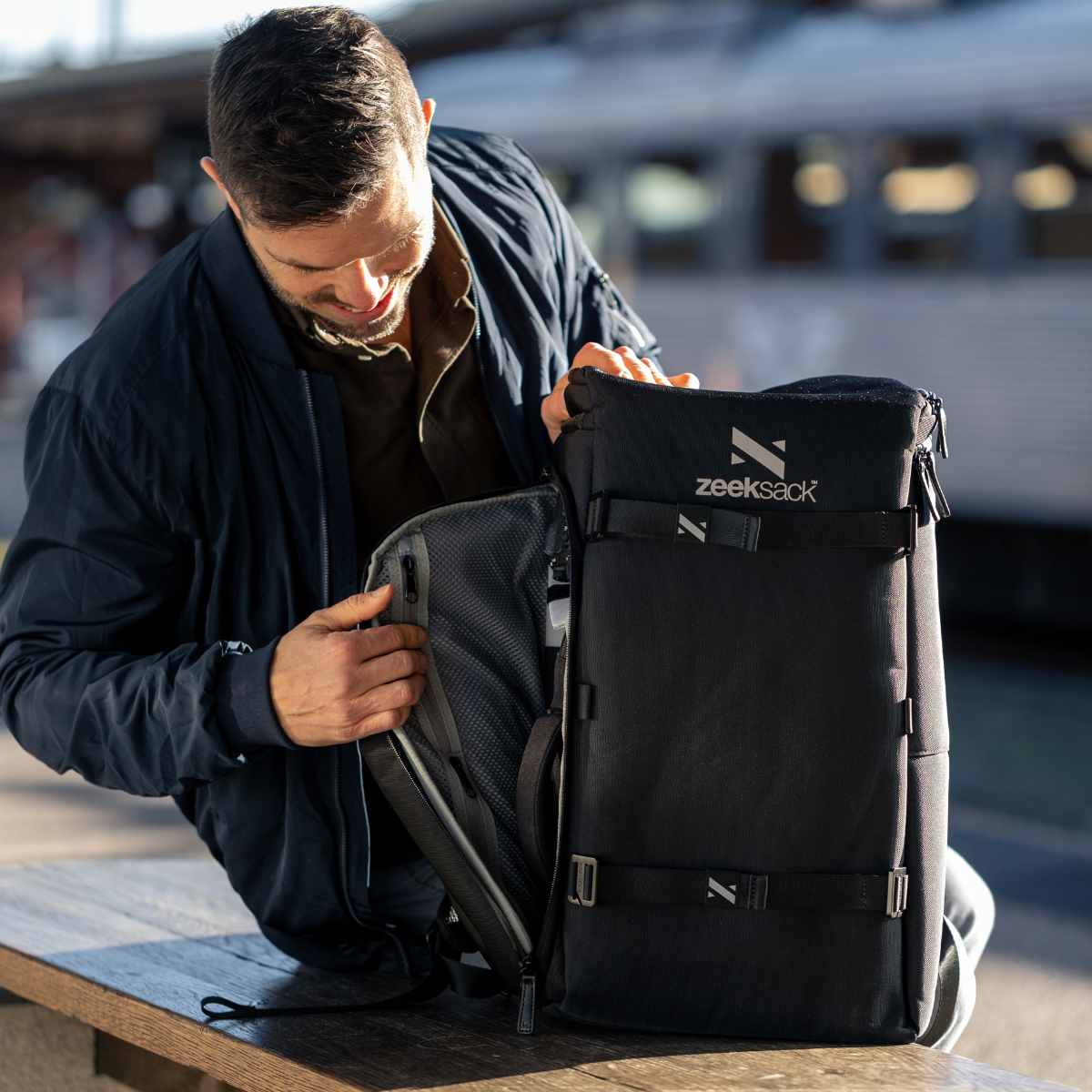 Man öppnar praktisk ryggsäck med en sidoöppning på tågstation